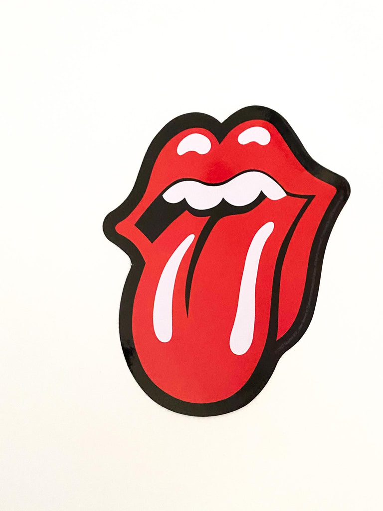 Sticker of a red mouth with a tongue sticking out, held by a hand against a white background. Rolling Stones logo sticker available at Rock & Roll Jane.