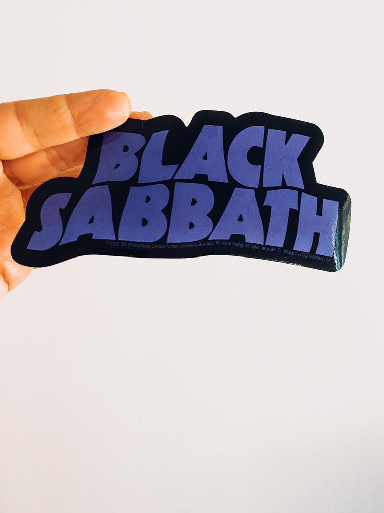 Black Sabbath purple wavy logo sticker held by a hand against a white background. Officially licensed merch at Rock & Roll Jane.