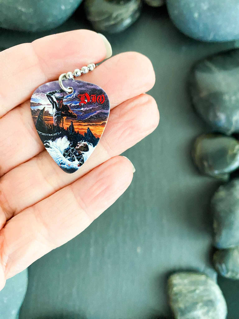 Ronnie James Dio guitar pick necklace with artwork from his "Holy Diver" album | 18" silver ball chain with extra cord included | Shop officially licensed band tees and band merch at Rock & Roll Jane