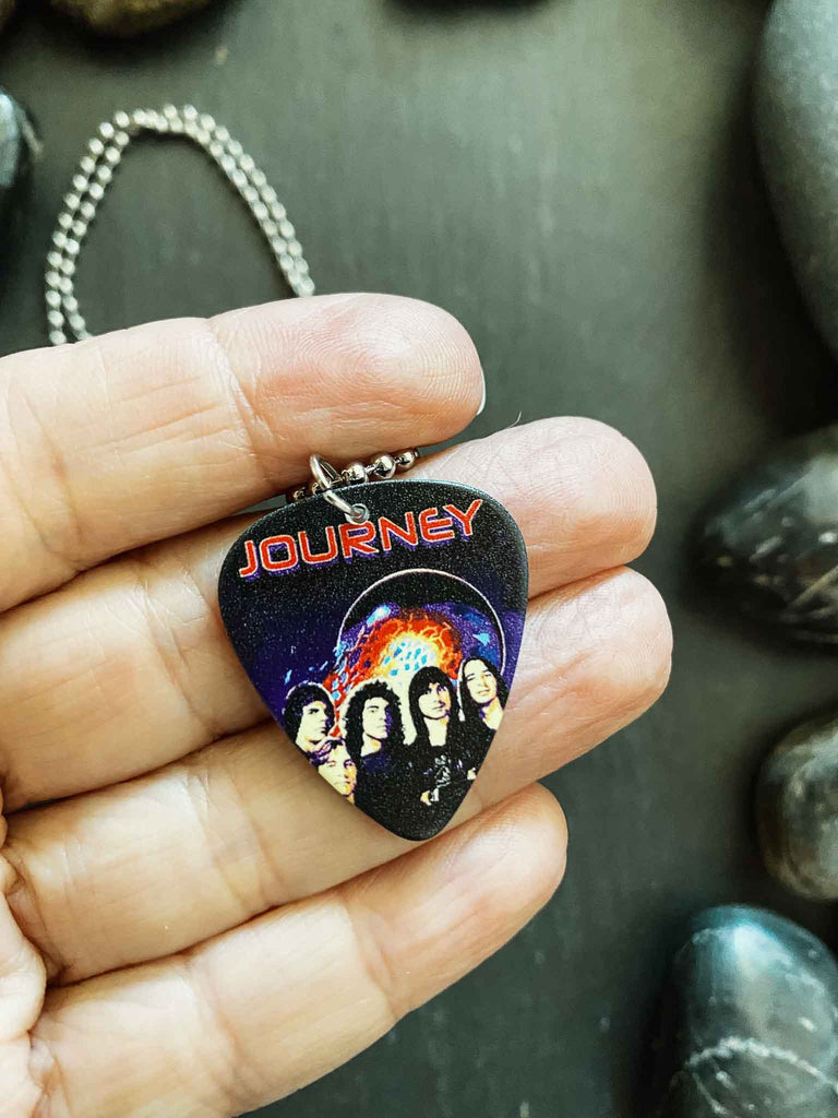 Journey guitar pick necklace featuring artwork from the band's "Escape" album, the Journey logo, and a band photo | Hangs on an 18" silver ball chain and comes with an extra black cord | Available at Rock & Roll Jane | We carry officially licensed band tees and accessories