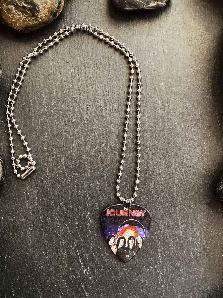 Journey guitar pick necklace featuring artwork from the band's "Escape" album, the Journey logo, and a band photo | Hangs on an 18" silver ball chain and comes with an extra black cord | Available at Rock & Roll Jane | We carry officially licensed band tees and accessories