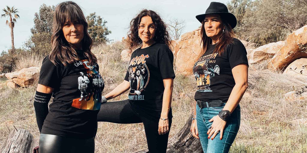 Three women wearing officially licensed band tees from Rock & Roll Jane. B 52s, AC/DC, Led Zeppelin tees