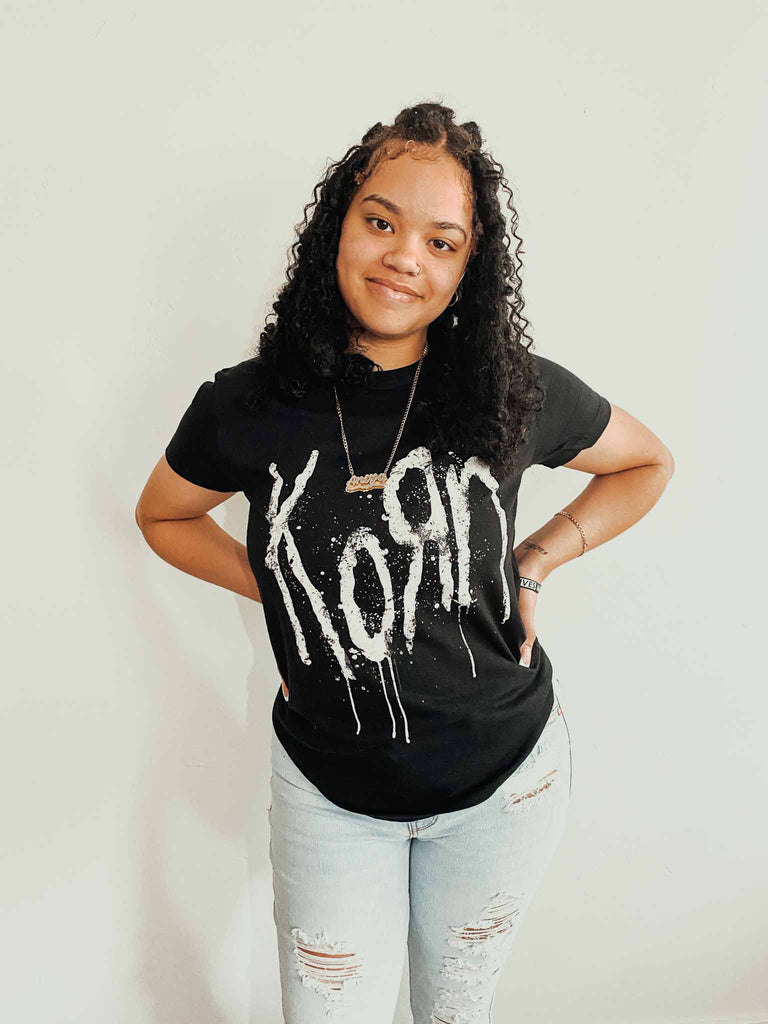 Girl modeling an officially licensed Korn t-shirt featuring the band logo in white on the front and the words "still a freak" on the back. Available at Rock & Roll Jane