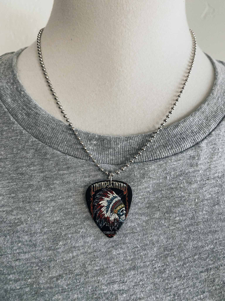 Lynyrd Skynyrd guitar pick necklace featuring a skull headdress and the band's logo | 18" silver ball chain with extra cord | Available at Rock & Roll Jane | We carry officially licensed band tees and accessories