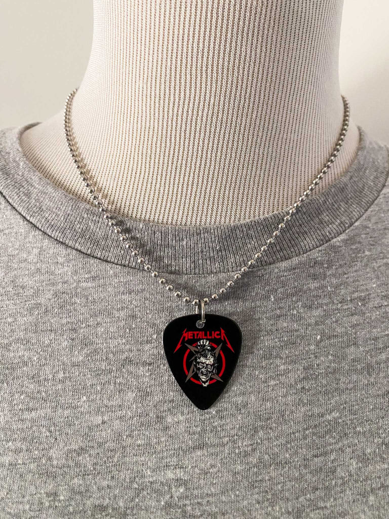 Metallica guitar pick necklace featuring the artwork from Damage, Inc. with a skull and the band's name in red. Band merch at Rock & Roll Jane. Displayed on a mannequin.