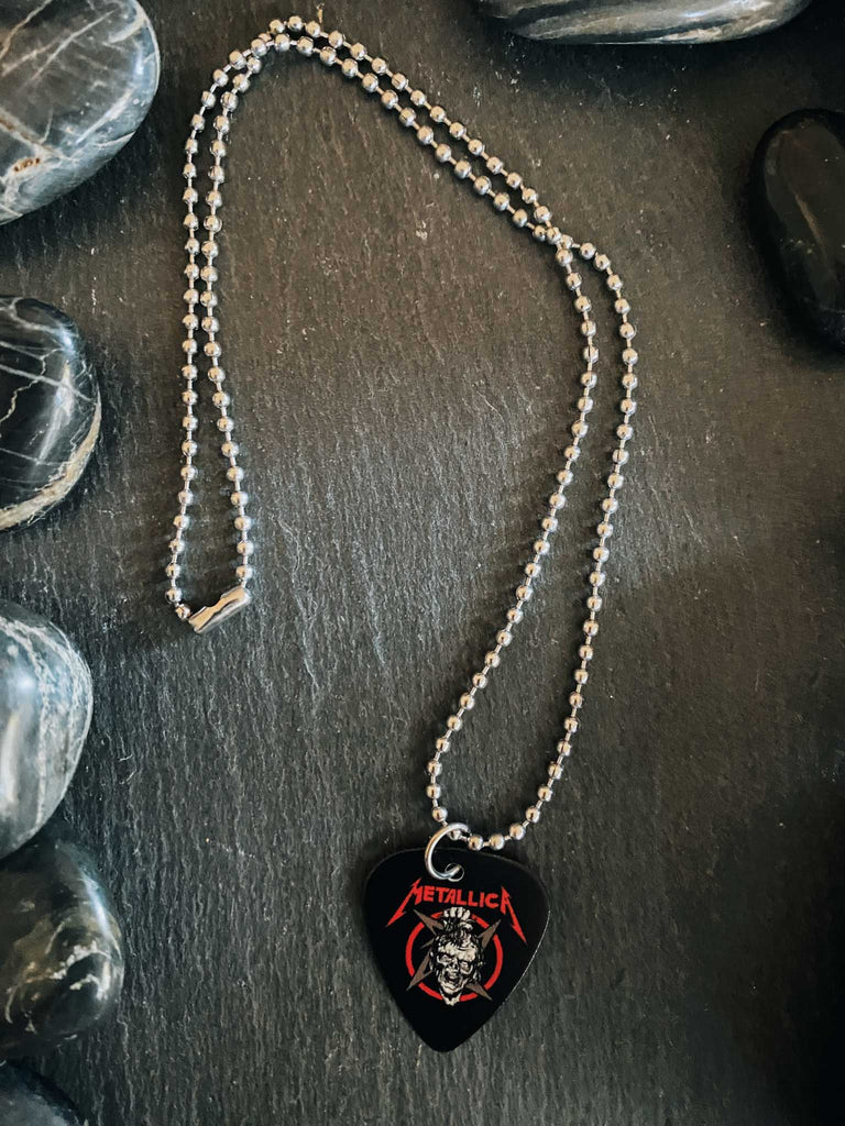 Metallica guitar pick necklace featuring the artwork from Damage, Inc. with a skull and the band's name in red. Band merch at Rock & Roll Jane.