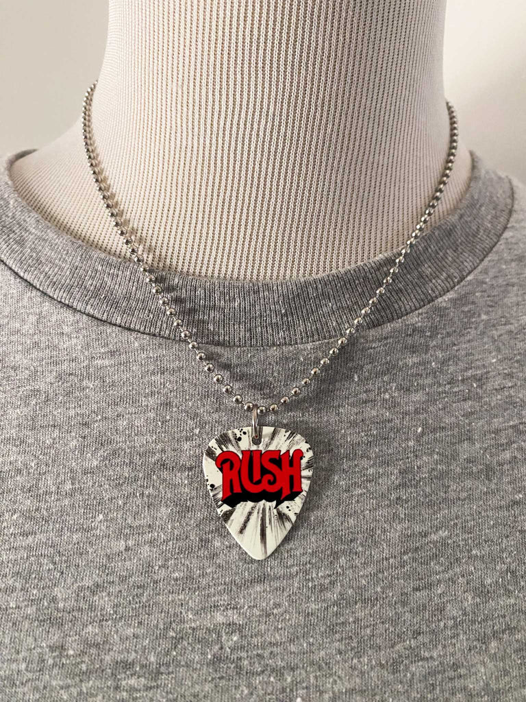 Rush guitar pick necklace on an 18" stainless steel ball chain. Band merch available at Rock & Roll Jane. Red logo lettering on a white and black background. Displayed on a mannequin.